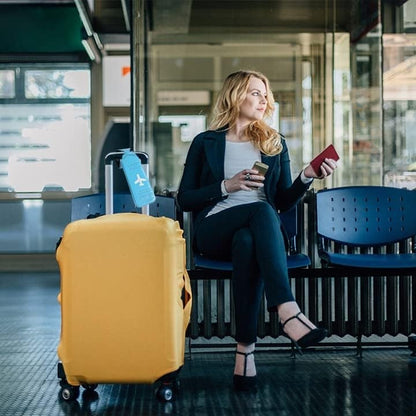 Waf Store Lebanon blue PVC luggage tag attached to a yellow suitcase next to a woman waiting at an airport terminal.