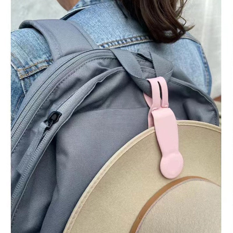 Waf Store Lebanon pink silicone hat clip attached to a grey backpack holding a beige hat for travel