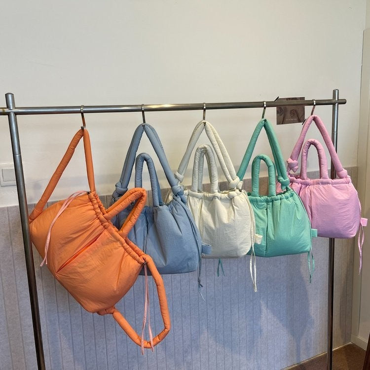 Waf Store Lebanon collection of colorful nylon puffer tote bags hanging on a rack in orange, blue, white, and pink.