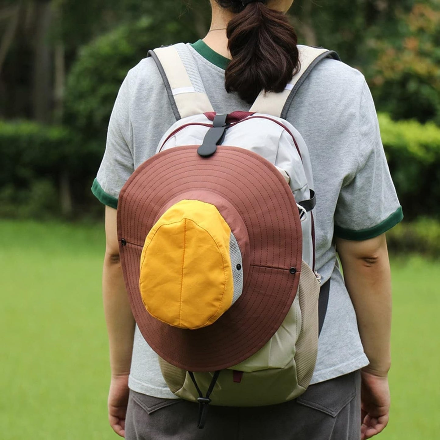 Waf Store Lebanon black silicone hat clip securing a brown and yellow sun hat to a backpack outdoors