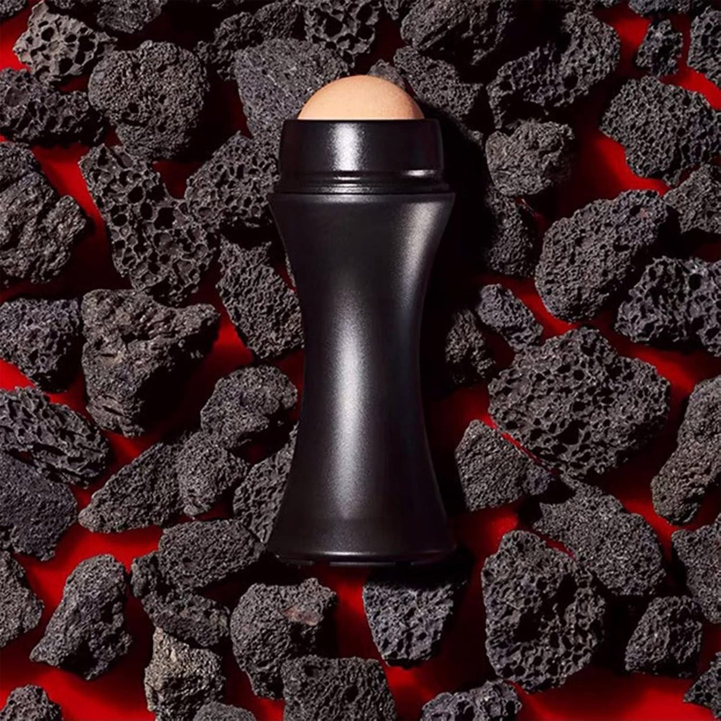 Waf Store Lebanon oil absorbing volcanic face roller with a matte black handle resting on dark porous volcanic rocks.