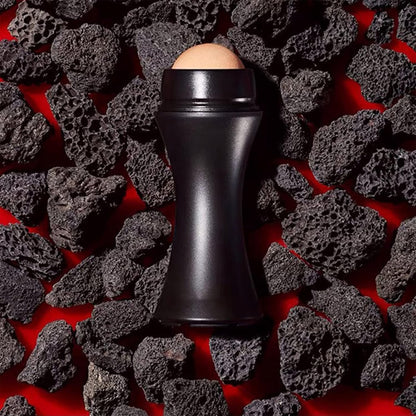 Waf Store Lebanon oil absorbing volcanic face roller with a matte black handle resting on dark porous volcanic rocks.